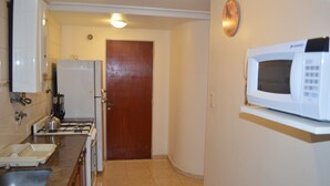 A kitchen with a stove, sink, microwave, and cabinets. - Catalina Norte Centro (Tucuman)