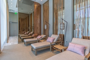 Relax in a serene spa room with lounge chairs, cushioned seats, and ambient lighting.