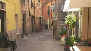 A narrow cobblestone street with outdoor seating and a restaurant named "La Creuza de M." - B&B Aria (Sarzana)