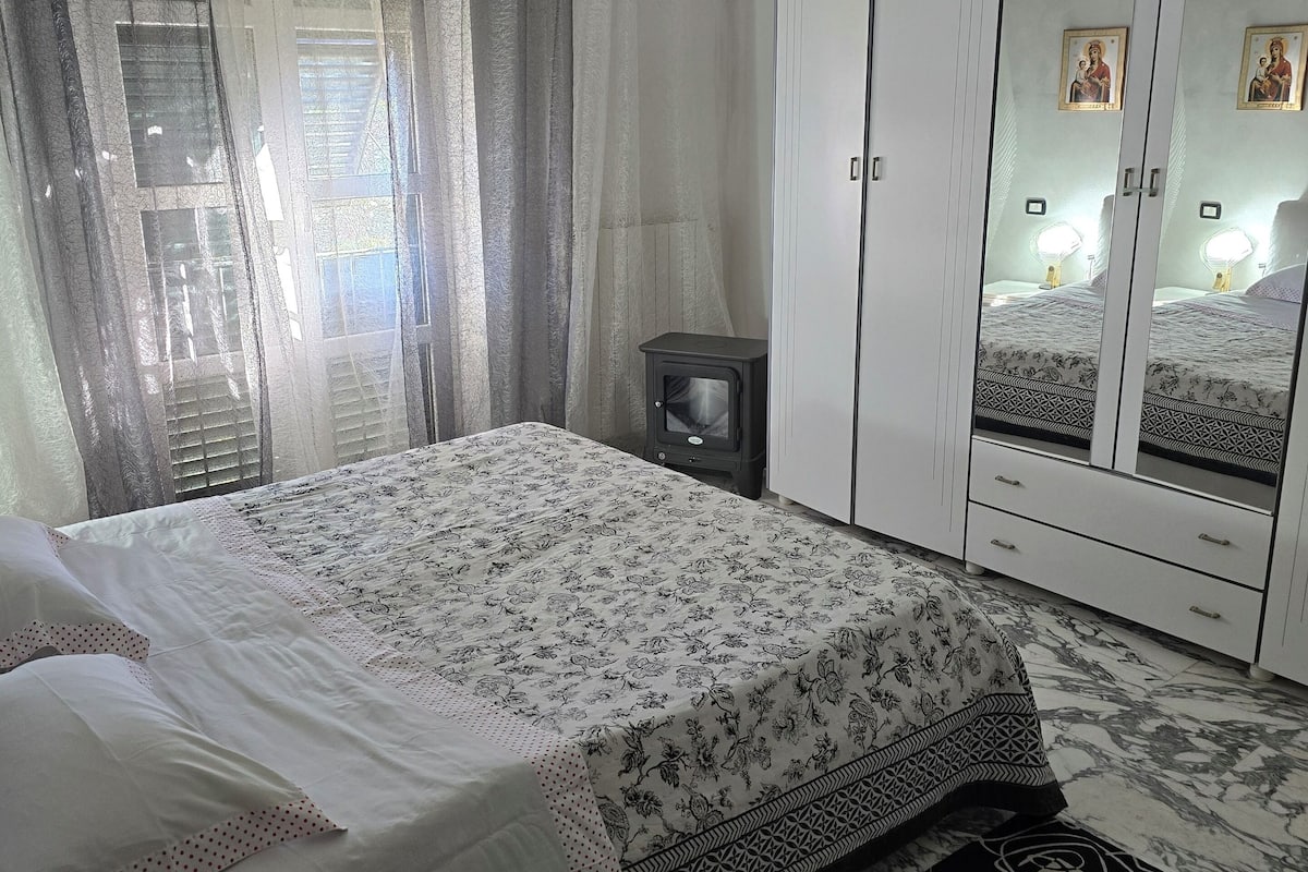 A bedroom with a bed, a wardrobe, a nightstand, and a small heater.