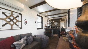 Ein gemütliches Wohnzimmer mit Ecksofa, Esstisch und Küchenzeile mit Barhocker.
