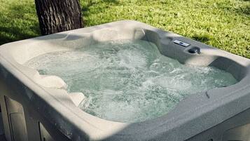 A hot tub with a control panel, surrounded by a grassy area.