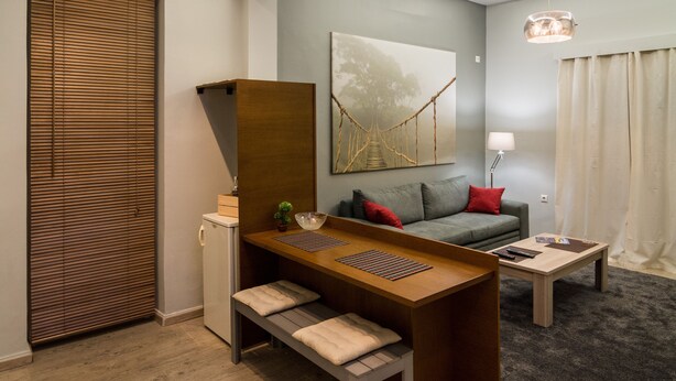 A modern living room with a wooden bench, a grey sofa, a coffee table, and a painting of a tree on the wall.