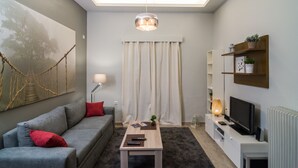 A modern living room with a grey sofa, a coffee table, a TV, and a bookshelf.