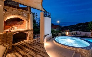 An outdoor patio with a brick fireplace and a hot tub. - Holiday Home Secret Garden (Jelsa)