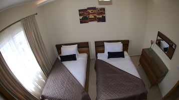 A hotel room with two beds, a nightstand, a mirror, and a wall-mounted artwork.