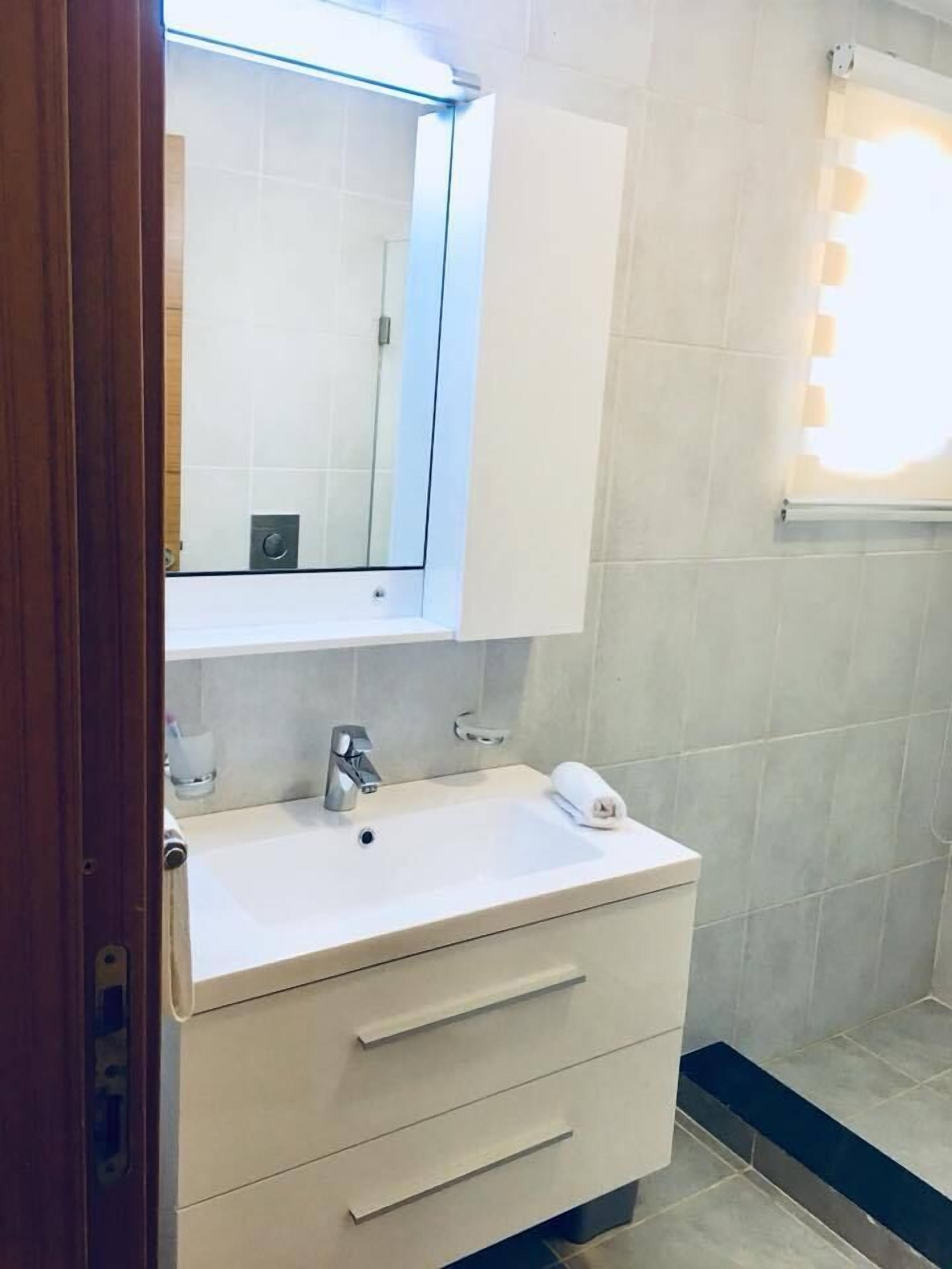 A bathroom with a white sink, a mirror, and a towel.