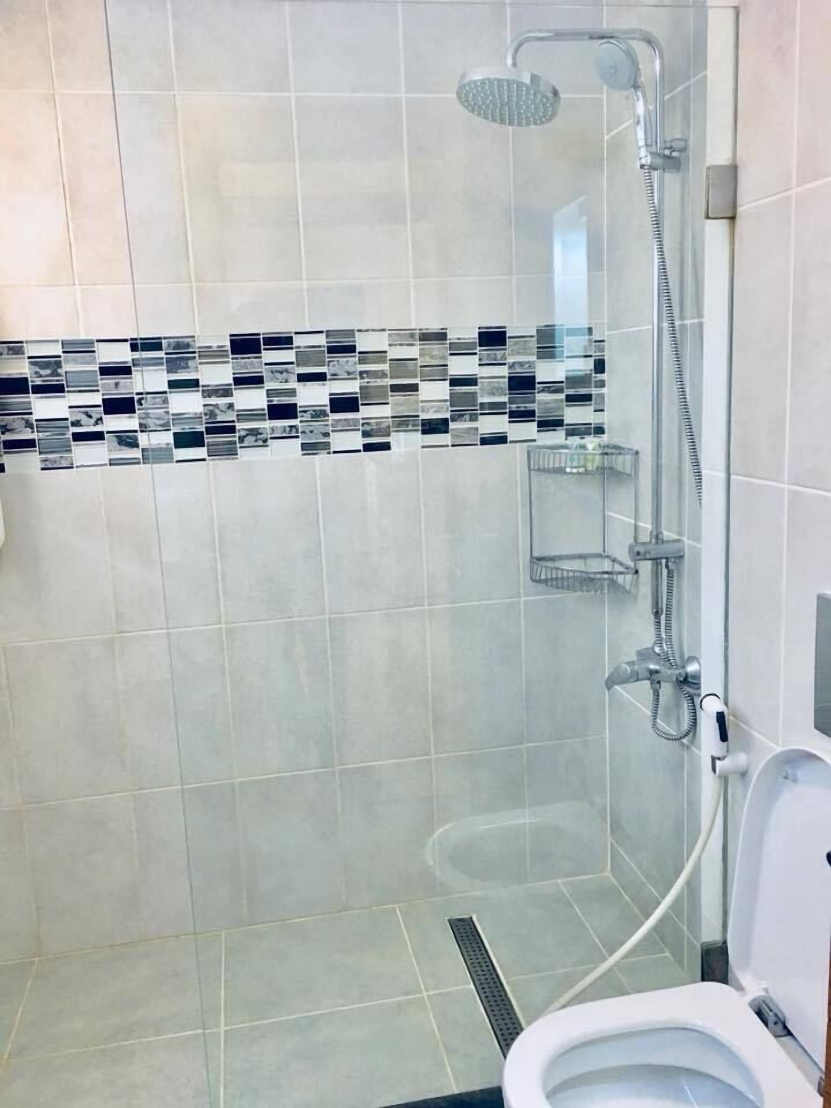 A bathroom with a shower, toilet, and a tiled backsplash.
