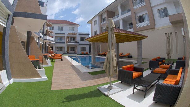 A rooftop pool area with lounge chairs, a swimming pool, and a covered seating area. - Pearl Hotel & Residence (Freetown)