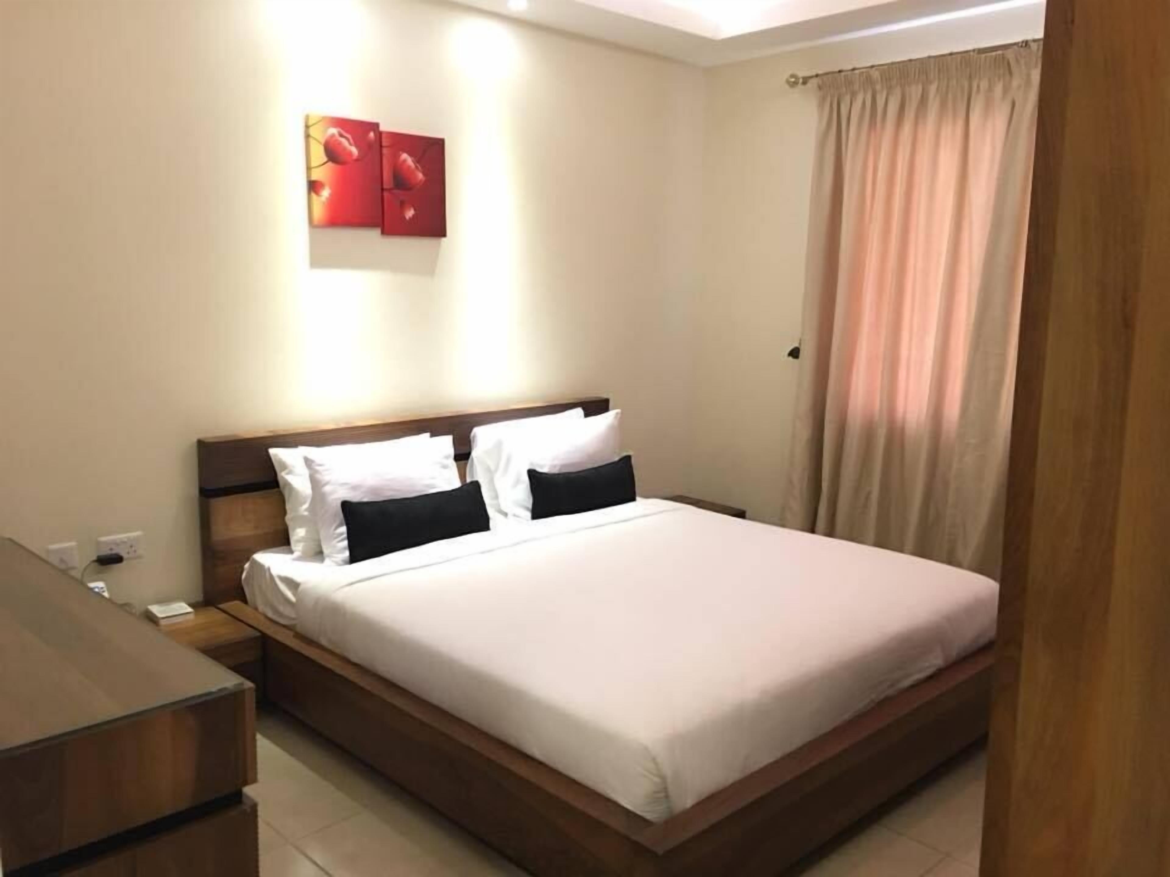 Una cama bien hecha con ropa de cama blanca y negra en una habitación de hotel.