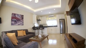 A modern living room with a sofa, coffee table, and a flat-screen TV mounted on the wall. - Pearl Hotel & Residence (Freetown)
