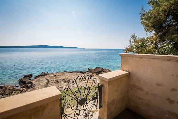 A balcony with a view of the sea and distant hills.