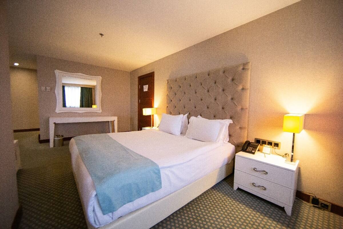 Ein Hotelzimmer mit einem großen Bett, Nachttischlampen, einem Schreibtisch und einem Telefon.