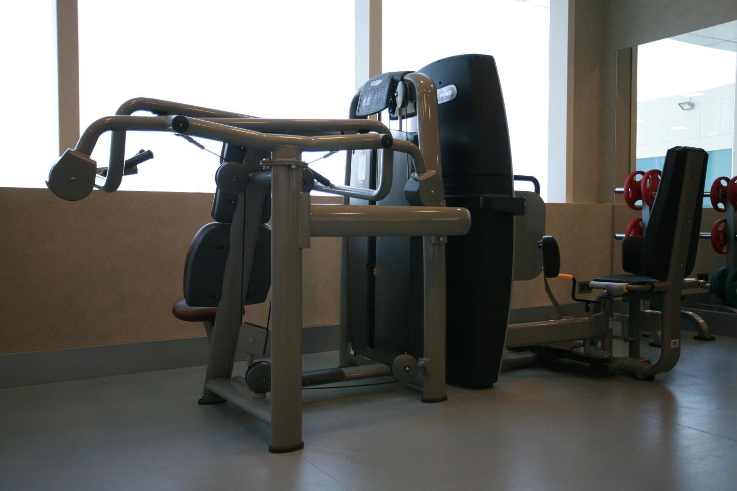 A gym with exercise equipment, large windows, and a mirror.