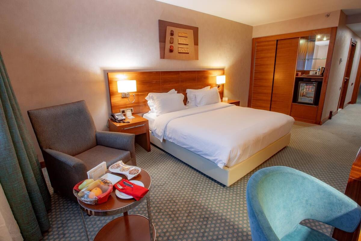 Ein Hotelzimmer mit Bett, Schreibtisch, Stuhl und einem kleinen Tisch mit Frühstücksangeboten.