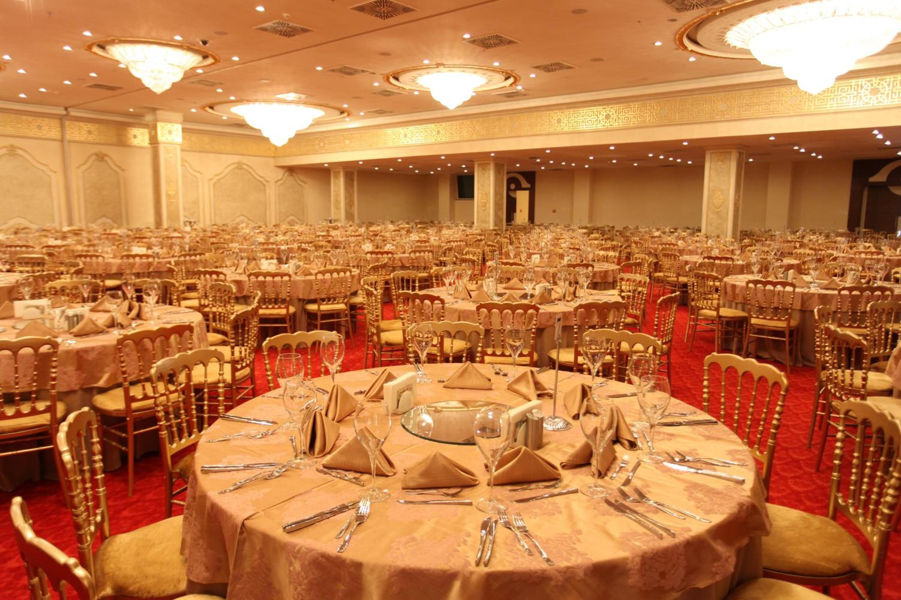 Una sala de banquet amb taules rodones preparades per dinar, disposades en files.