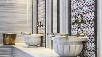 Experience a luxurious bathroom with three marble basins, gold accents, and a striking tile pattern.