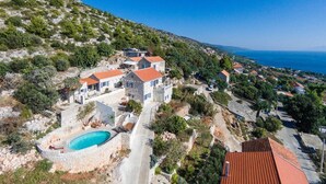 A coastal property with a swimming pool, stone walls, and terraced houses. - Old Tree Villa (Jelsa)