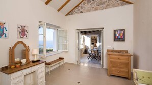 A room with a wooden dresser, a bench, a table with chairs, and a view through an open door. - Old Tree Villa (Jelsa)