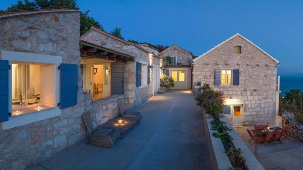 A stone building with a covered patio, a dining area, and a view of the sea. - Old Tree Villa (Jelsa)