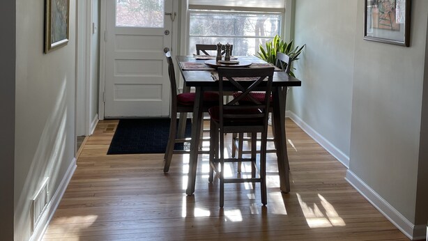 A dining area with a ceiling fan, a table with chairs, and two windows.