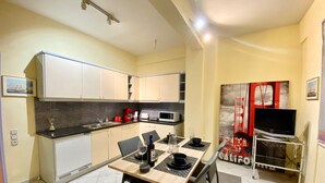 A compact kitchen with modern appliances, a dining area with a table set for two, and a TV on a stand. - Chic Elegant New Apartment - Kolonaki (Athens)