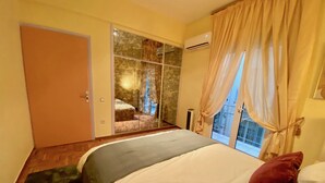 A bedroom with a bed, a sliding glass door leading to a balcony, and an air conditioning unit. - Chic Elegant New Apartment - Kolonaki (Athens)