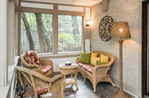 A cozy room with wicker furniture, a small table, and a floor lamp.