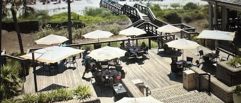 A beach club with outdoor seating, umbrellas, and a view of the beach.