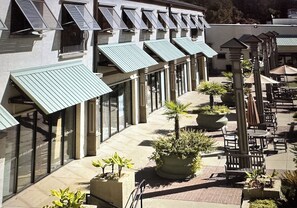 A building with multiple balconies, large windows, and outdoor seating areas with potted plants.
