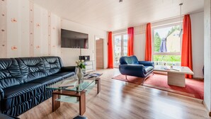Una sala de estar moderna con un sofá de cuero negro, una mesa de centro de vidrio y un sillón azul.