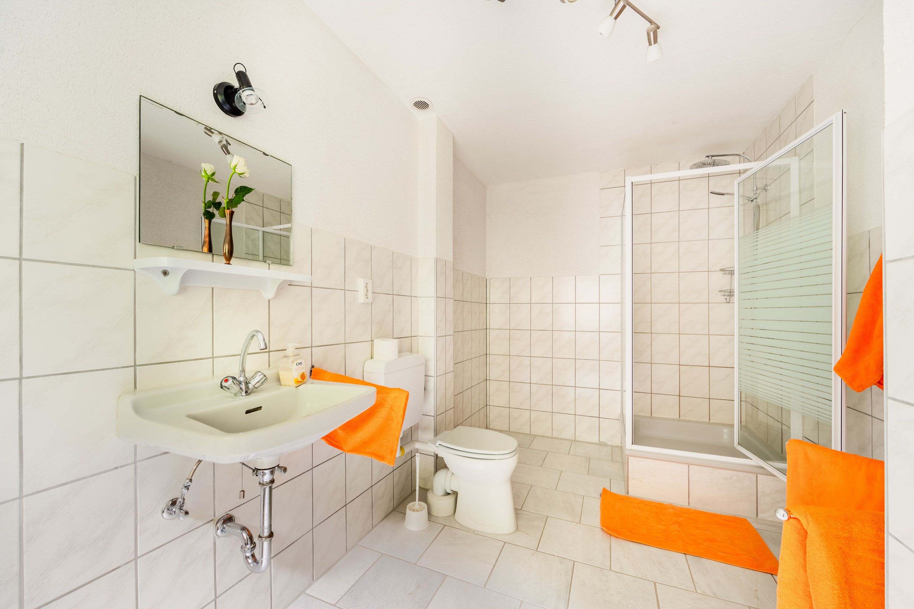 Un baño moderno con lavamanos, espejo, inodoro y ducha.