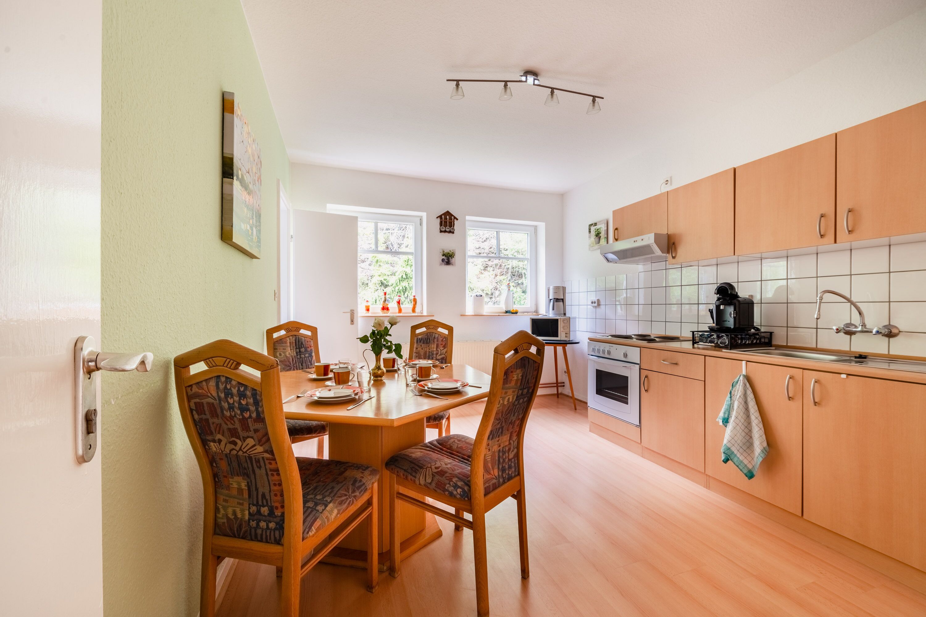 Une cuisine moderne avec des meubles en bois, une table à manger avec des chaises et une fenêtre qui laisse entrer la lumière naturelle.