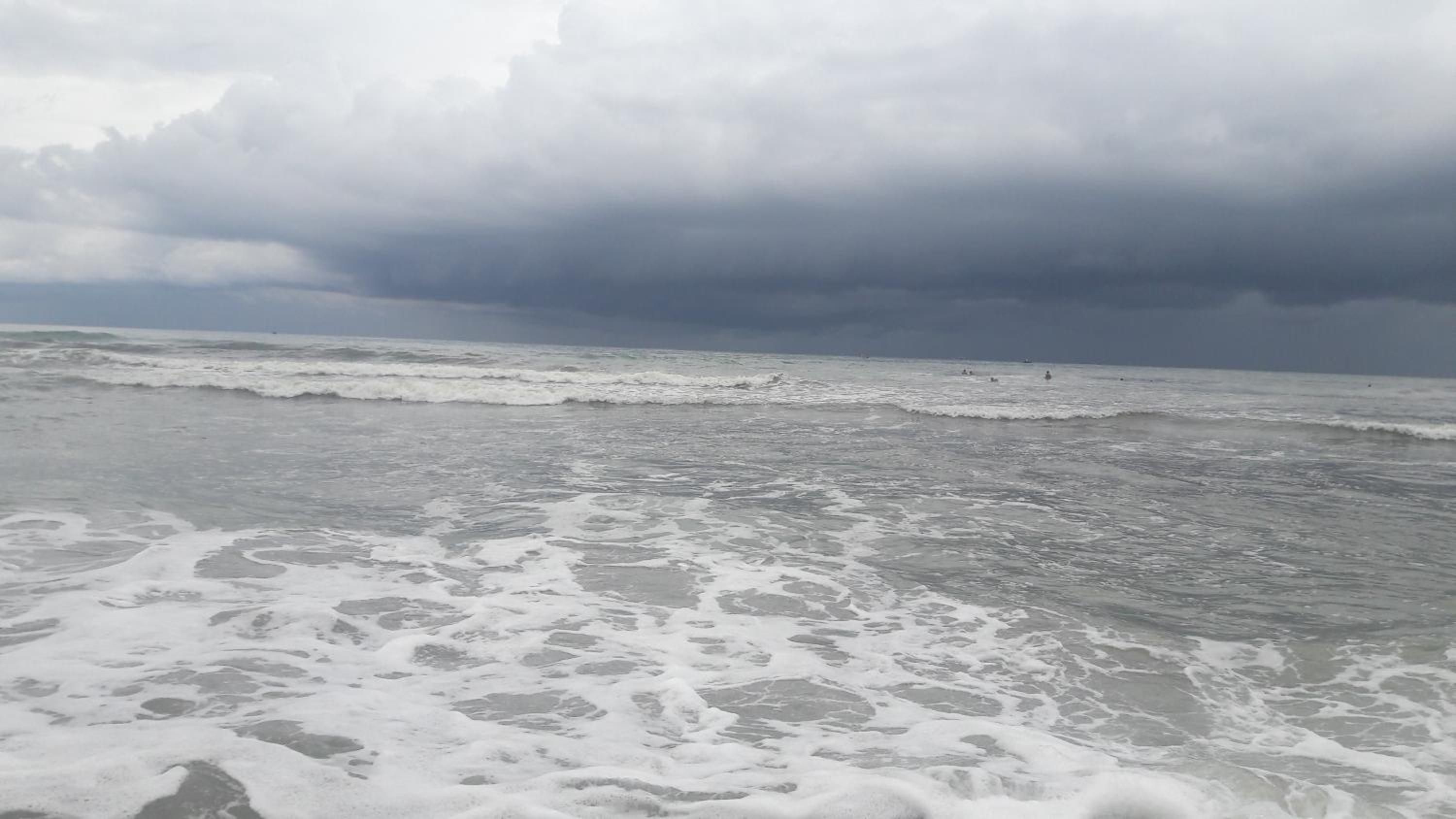 A beach with waves and a cloudy sky.