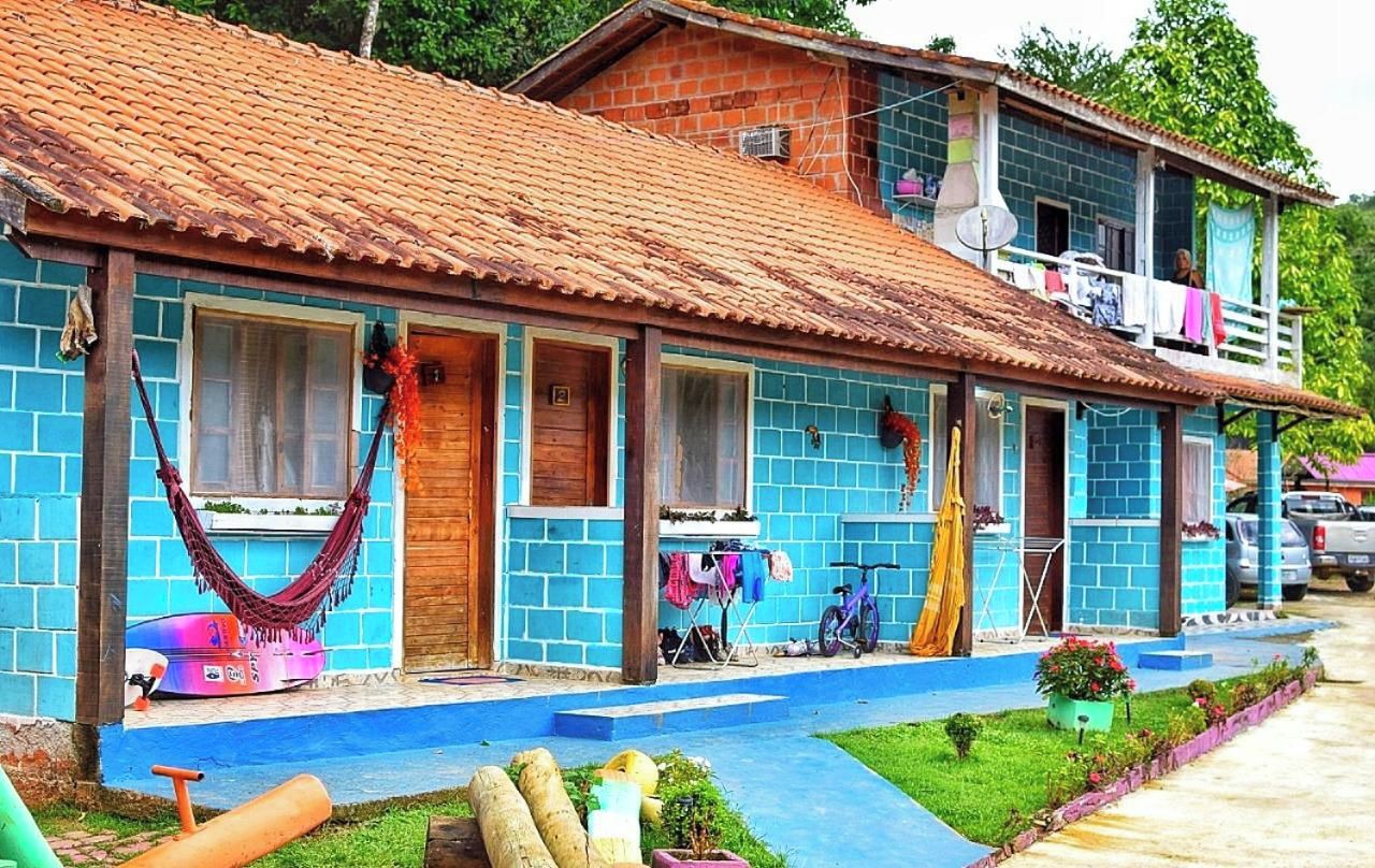 Uma casa de dois andares com telhado de telhas, varanda e um pequeno jardim.