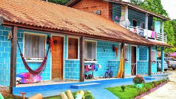 Uma casa de dois andares com telhado de telhas, varanda e um pequeno jardim.