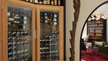 Una bodega con armarios de vidrio llenos de botellas de vino, una escultura de madera rústica y una zona de estar acogedora con un tapete rojo.