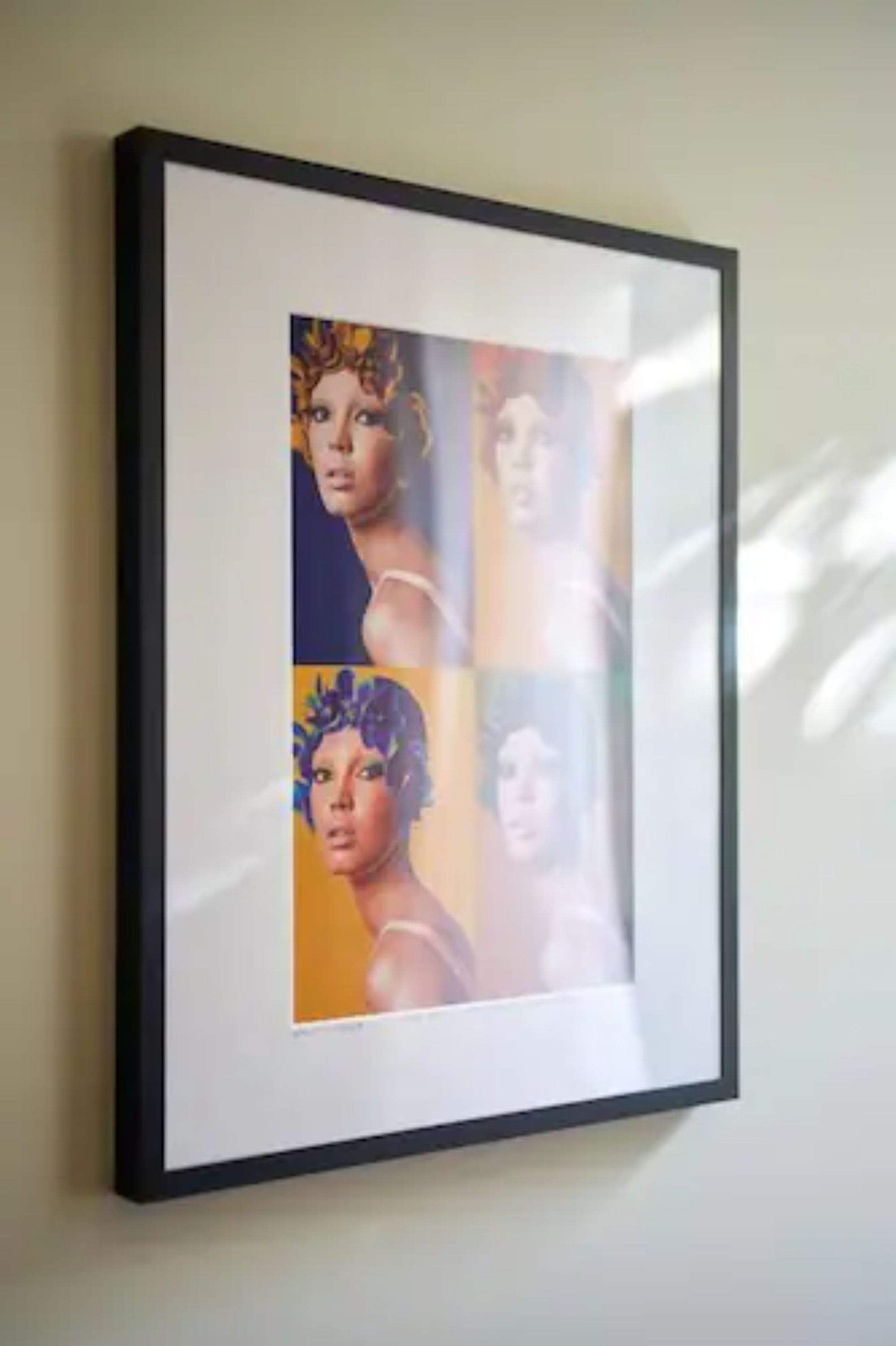 Une œuvre d’art encadrée, composée de plusieurs panneaux, est accrochée à un mur.