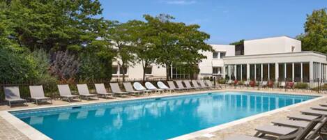 A pool area with lounge chairs and a building in the background.