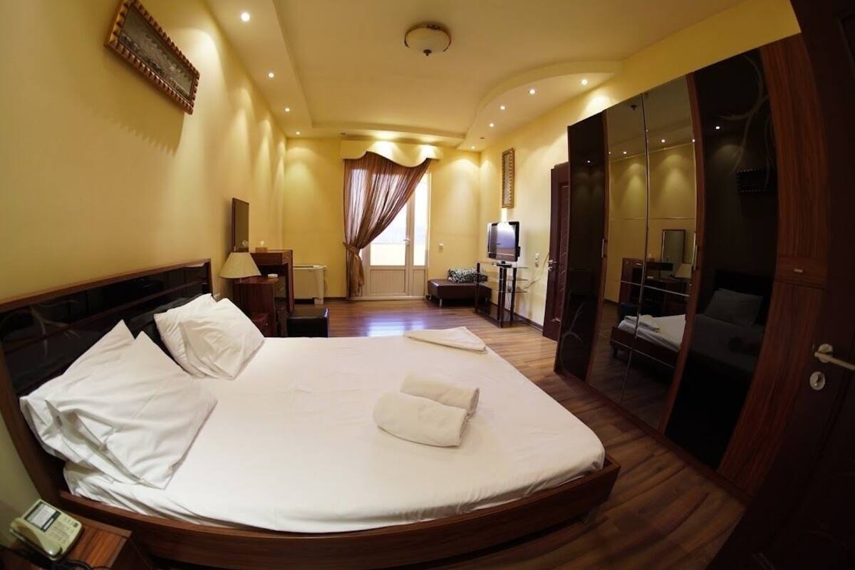 Een hotelkamer met een groot bed, een televisie, een bureau en een spiegel.