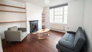 A living room with a fireplace, a sofa, a coffee table, and a large window. - Central London 2BR Apartment in Waterloo (London)