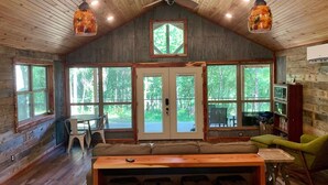 L’intérieur d’une cabine comprenant un coin repas, de grandes fenêtres et un ventilateur de plafond.
