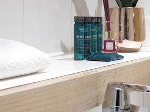 A bathroom counter with a white towel, a shower gel bottle, and a diffuser oil bottle. - Tudors eSuites City Centre Apartment (Birmingham)