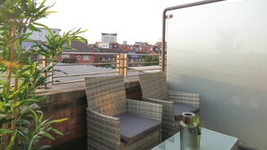 A terrace with wicker furniture, a glass table, and a view of residential buildings. - Tudors eSuites City Centre Apartment (Birmingham)