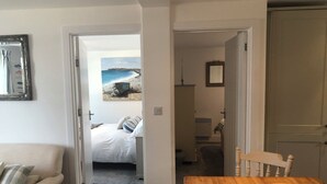 Ein Schlafzimmer mit einem Bett, Blick auf den Strand und einem Holztisch mit einer Schüssel.