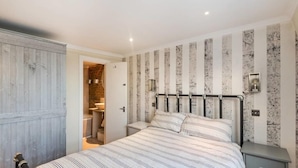 A bedroom with a bed, a wardrobe, and a bathroom visible through an open door. - Lovely 1BR Flat Walk to Hyde Park (London)