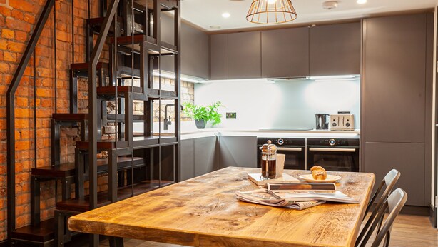 Cozinha moderna com mesa de madeira, cadeiras e máquina de café.