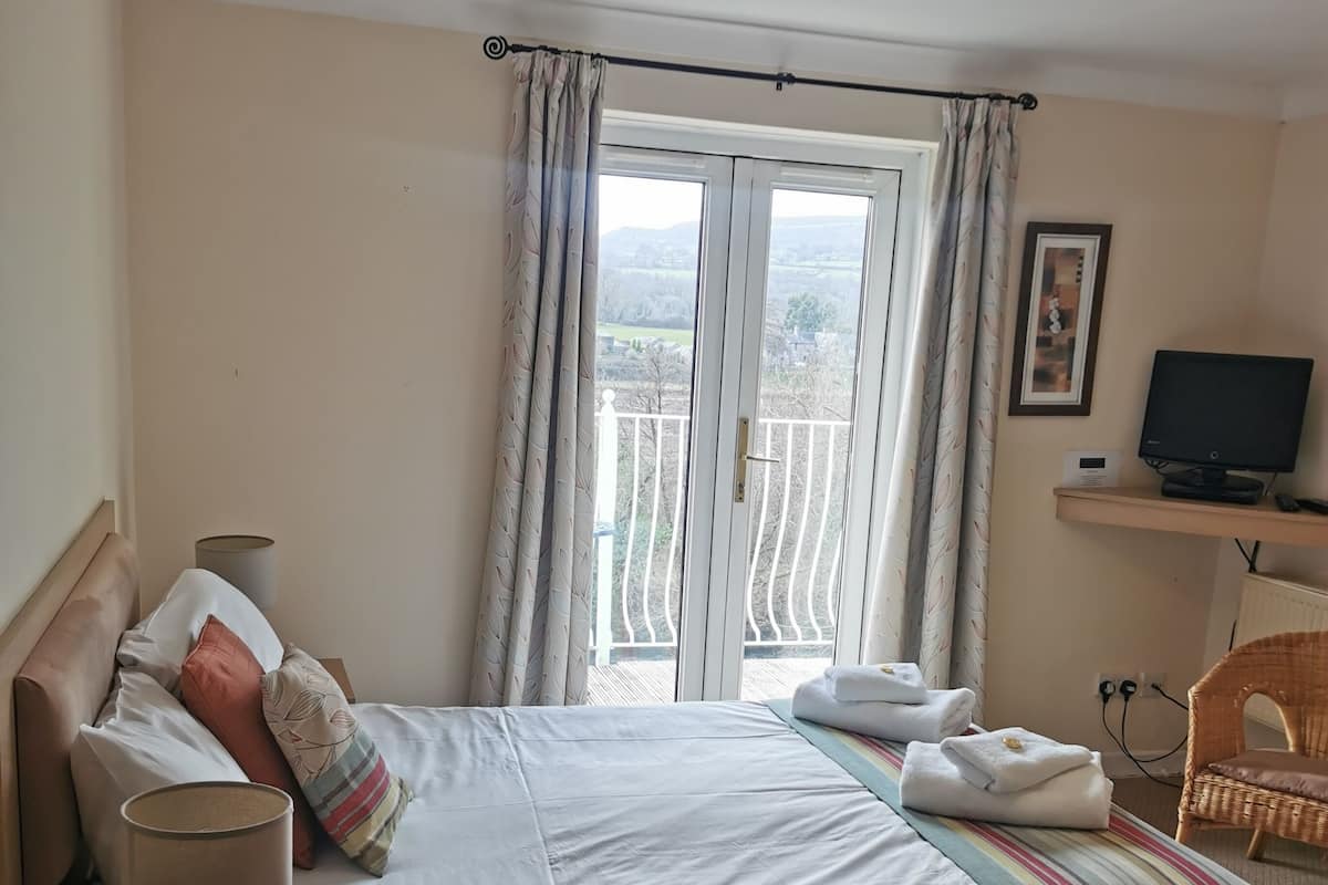 A hotel room with a bed, a desk, a chair, a television, and a window with curtains.