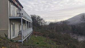 Een gebouw met een balkon en uitzicht op een rivier en heuvels op de achtergrond.