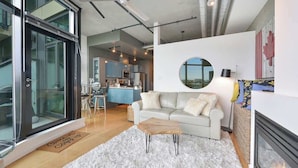 A modern living room with a white sofa, a round mirror, and a fireplace. - Harbourview Executive Condo (Victoria)